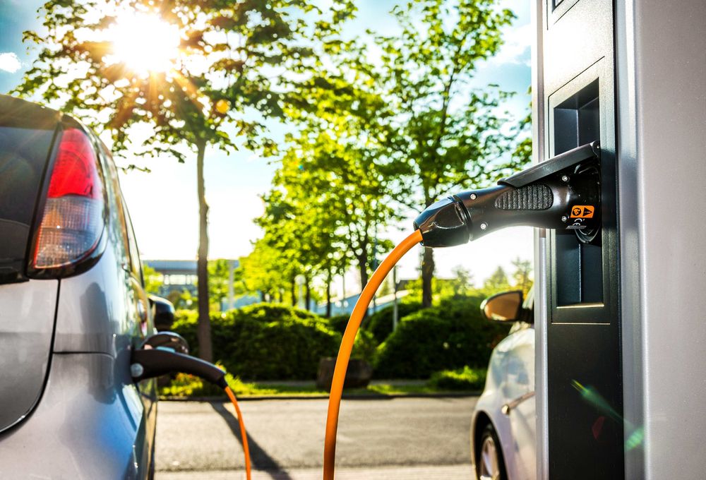 E-Auto auf einem Parkplatz, das an einer Ladestation aufgeladen wird.